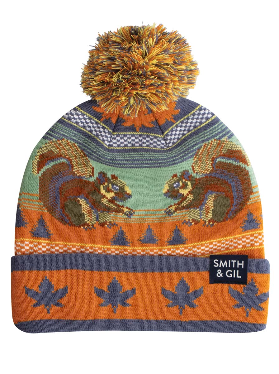 A multicolored beanie with a squirrel pattern and a pom pom on top.