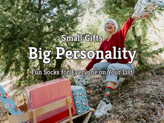 Fun novelty socks as stocking stuffers [image of man carrying santa sack wearing Ho Ho Ho socks in green]