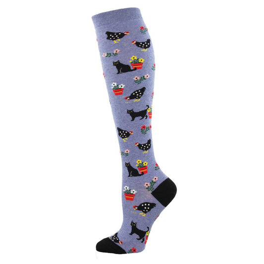 A pair of knee-high socks with a pattern of cats, flowers, and dots on a blue background.