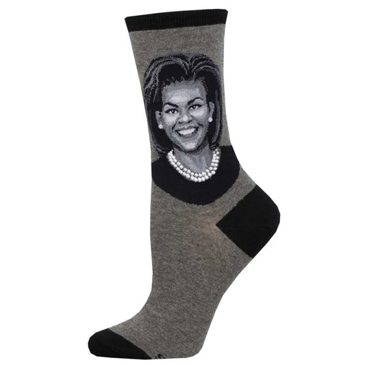 A pair of cotton crew socks featuring a portrait of Michelle Obama, predominantly in gray and black colors.