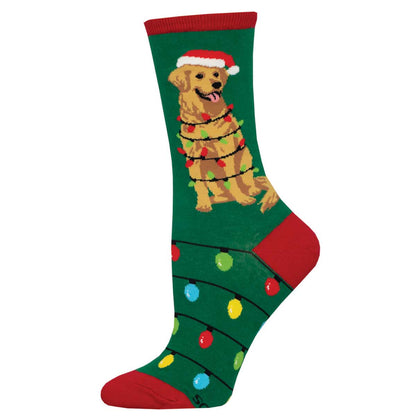 A pair of women's crew socks with a pattern of a dog wearing a Santa hat and Christmas lights, set against a green background.
