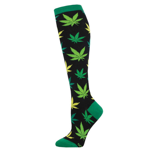 A pair of knee-high socks with a pattern of green and yellow cannabis leaves on a black background, with green at the heel and toe.