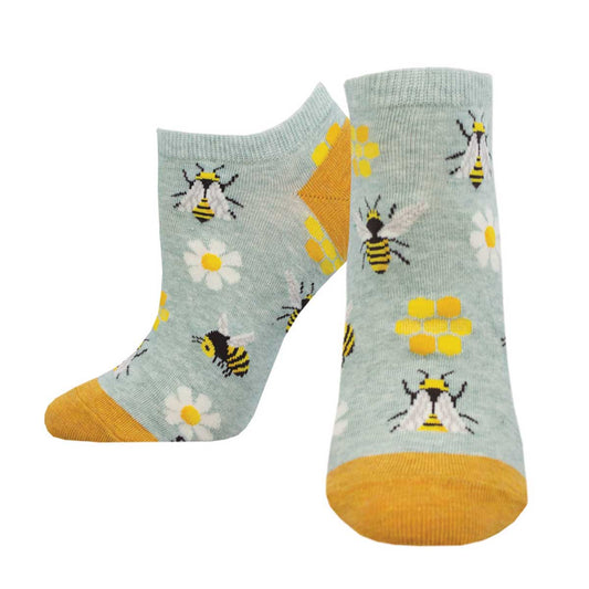 A pair of light green ankle socks with a pattern of bees, flowers, and honeycomb, and yellow accents on the sole.