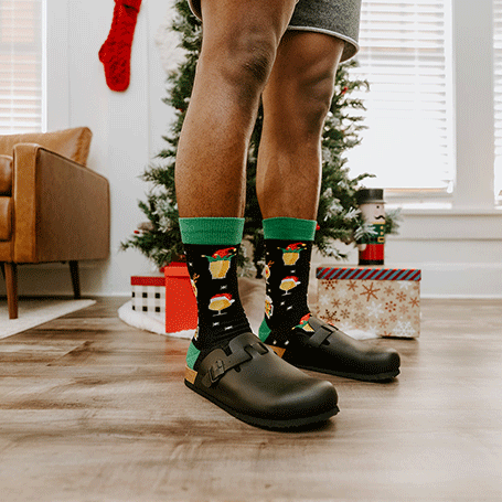 Person wearing festive socks with a Christmas-themed room in the background