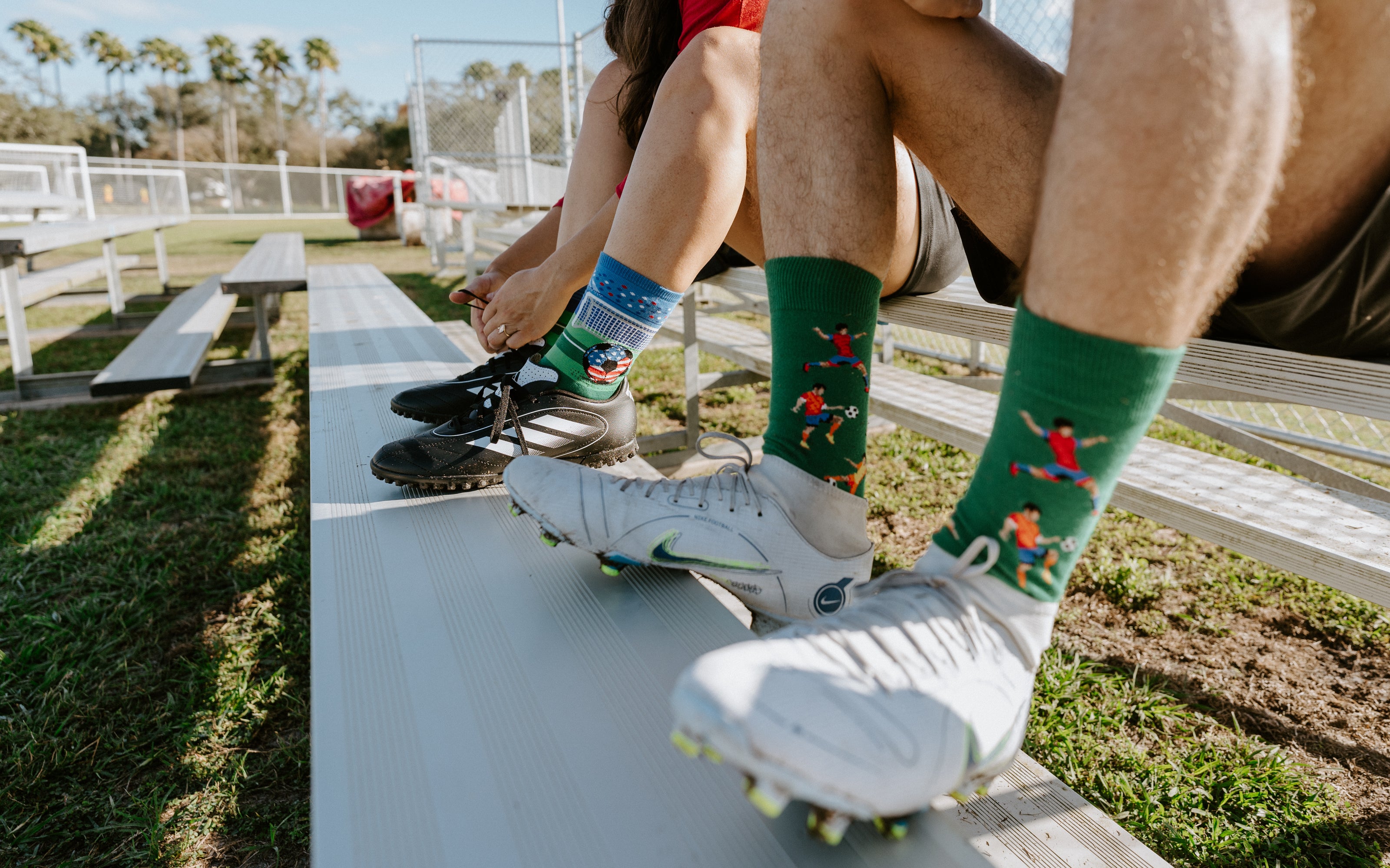 A close-up of men's Kicking It socks and women's Soccer's Biggest Stage socks in cleats.