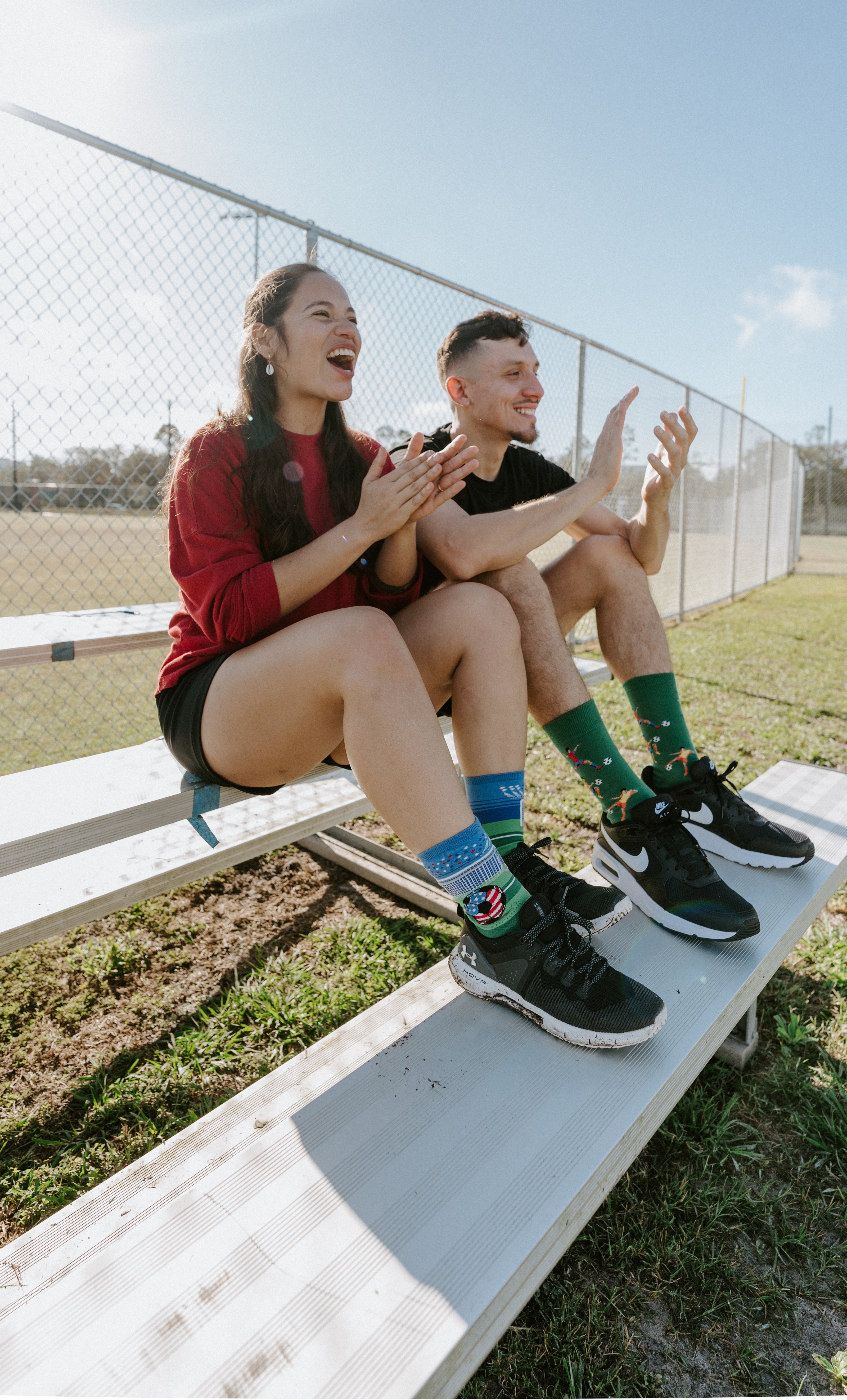 "two people clapping on bleachers wearing soccer socks"