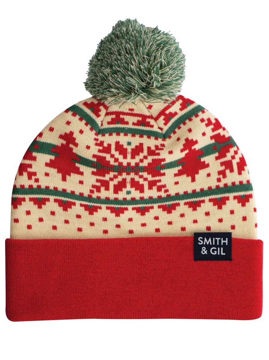 A Fair Isle patterned beanie in red, white, and green with a foldable cuff and a pom pom on top.