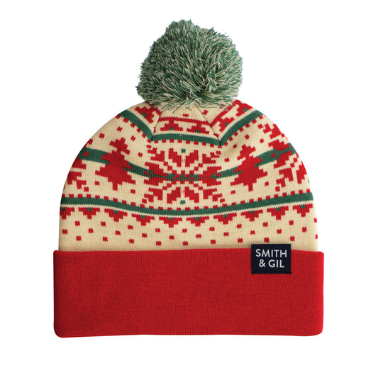 A Fair Isle patterned beanie in red, white, and green with a foldable cuff and a pom pom on top.