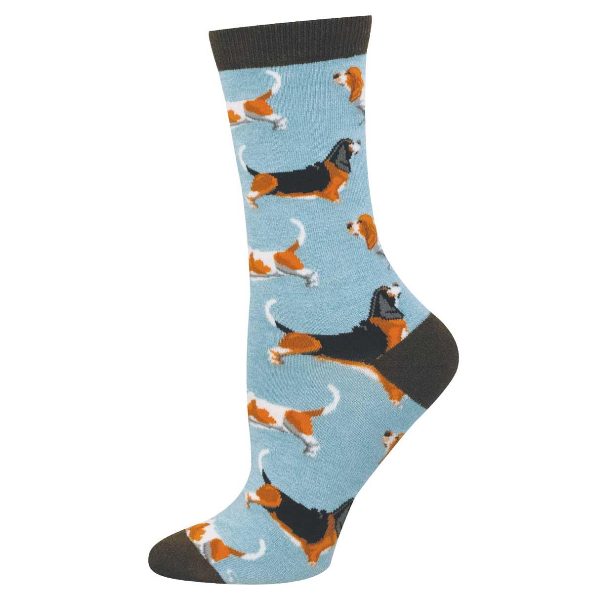 A single crew sock with a light blue background printed with basset hound illustrations in black, white, and orange, featuring dark brown ribbed cuffs, heels, and toes.