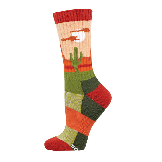 A colorful crew sock with a desert landscape design, featuring a cactus and sunset, predominantly in orange, red, and green shades.