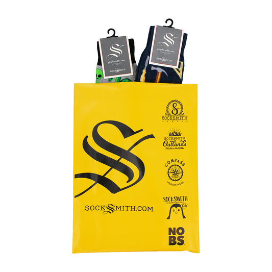 A yellow Socksmith gift bag with black printed logos and text, holding two packaged pairs of men's cotton novelty socks.